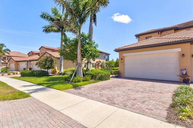 23528 Awabuki Dr Unit 101, Venice, FL 34293 - mediterranean / spanish house featuring stucco siding, decorative driveway, a tiled roof, and a residential view