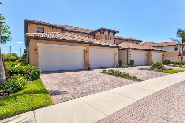 23528 Awabuki Dr Unit 101, Venice, FL 34293 - mediterranean / spanish-style home with stucco siding, decorative driveway, an attached garage, and a tiled roof