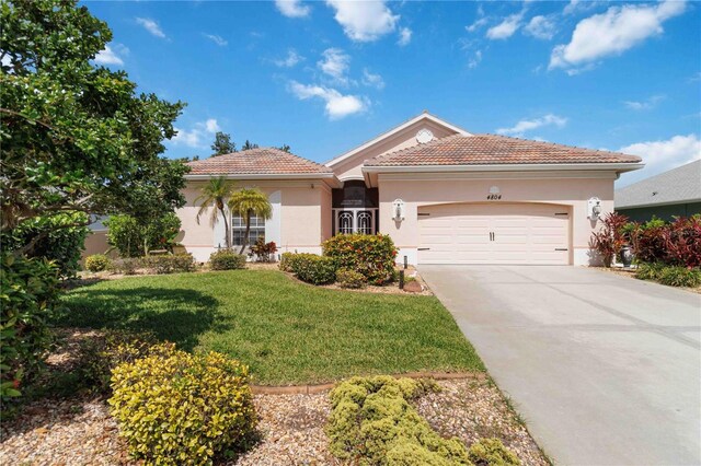 4804 Jacaranda Heights Dr, Venice, FL 34293 - view of front of house with an attached garage, concrete driveway, a front lawn, stucco siding, and a tile roof