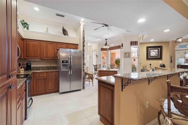 4804 Jacaranda Heights Dr, Venice, FL 34293 - kitchen with stainless steel appliances, ceiling fan, a breakfast bar, decorative backsplash, and stone counters