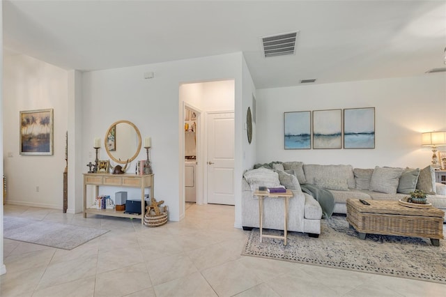living room featuring washer / clothes dryer, light tile patterned floors, and baseboards
