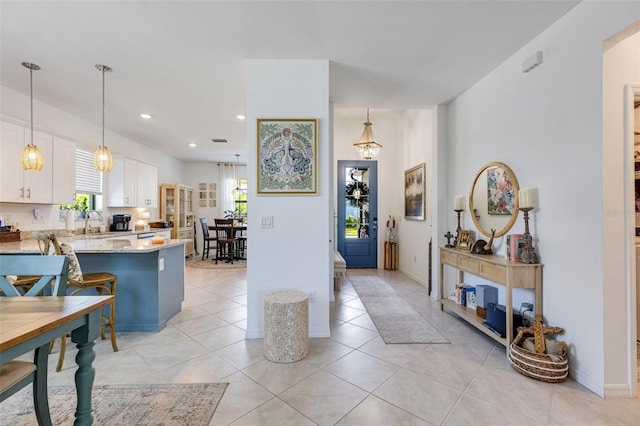 kitchen featuring white cabinetry, light stone countertops, a peninsula, pendant lighting, and light tile patterned flooring