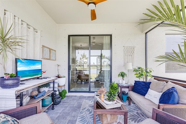 living area with a ceiling fan and brick patterned flooring