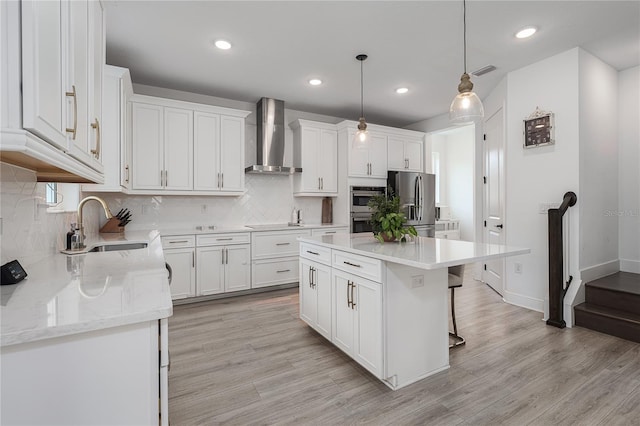 5651 Trevesta Pl, Palmetto, FL 34221 - kitchen featuring wall chimney range hood, stainless steel appliances, white cabinetry, light wood-style floors, and recessed lighting