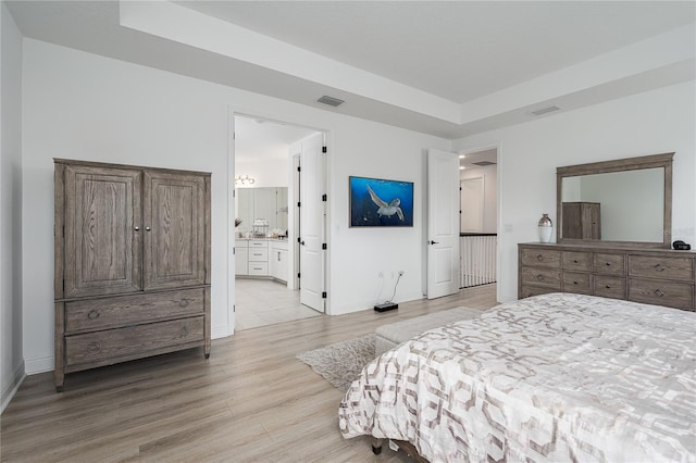 5651 Trevesta Pl, Palmetto, FL 34221 - bedroom with light wood-style floors, a tray ceiling, and connected bathroom