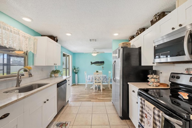 217 High Point Dr Unit 217A, Englewood, FL 34223 - kitchen with appliances with stainless steel finishes, a sink, white cabinets, ceiling fan, and a textured ceiling