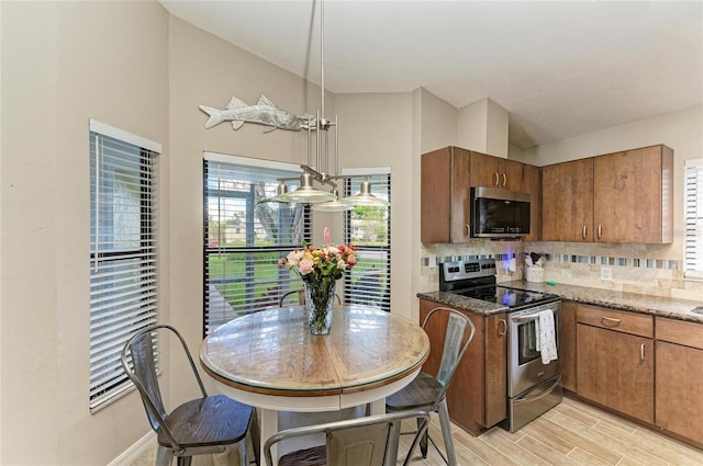 4115 2nd Ave NW, Bradenton, FL 34209 - kitchen featuring appliances with stainless steel finishes, tasteful backsplash, brown cabinetry, light wood-style flooring, and vaulted ceiling