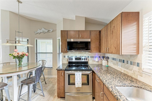 4115 2nd Ave NW, Bradenton, FL 34209 - kitchen with appliances with stainless steel finishes, lofted ceiling, brown cabinets, backsplash, and stone counters