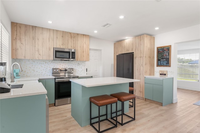 2715 Herwald St, Sarasota, FL 34231 - kitchen with appliances with stainless steel finishes, a sink, a kitchen bar, light wood-type flooring, and light countertops
