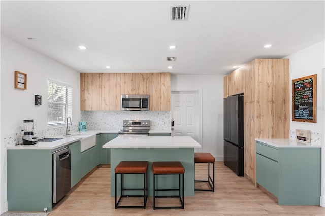 2715 Herwald St, Sarasota, FL 34231 - kitchen with stainless steel appliances, a sink, a center island, a kitchen bar, and light wood-style floors