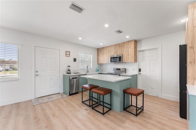 2715 Herwald St, Sarasota, FL 34231 - kitchen featuring stainless steel appliances, a breakfast bar, light wood-type flooring, a center island, and recessed lighting