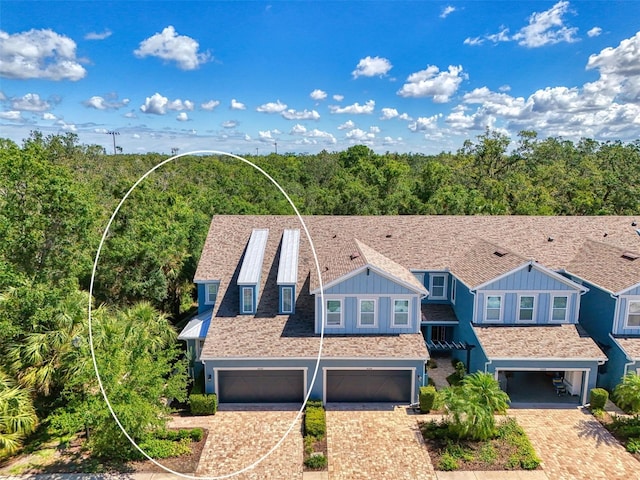 4500 Chinkapin Dr, Sarasota, FL 34232 - view of front facade with board and batten siding, an attached garage, driveway, and a view of trees