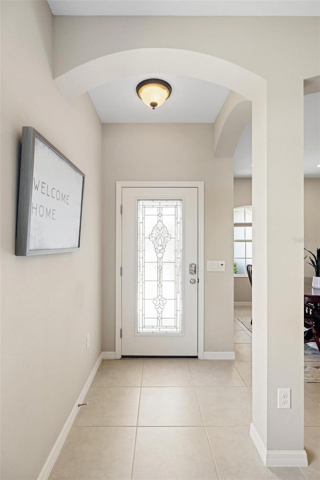 tiled foyer entrance with arched walkways and baseboards