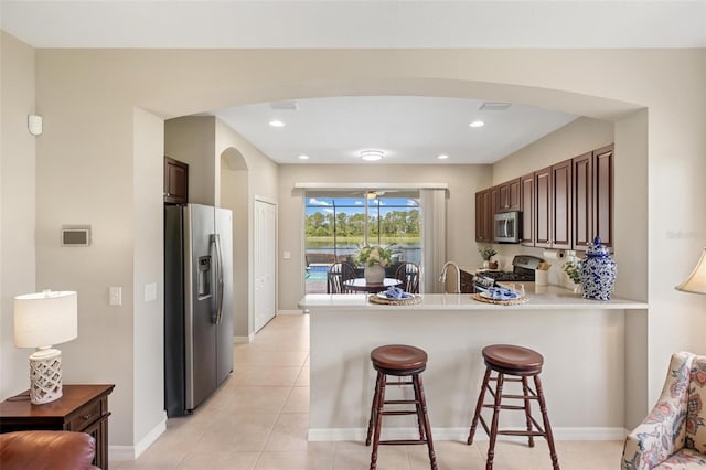 kitchen with stainless steel appliances, arched walkways, a peninsula, a breakfast bar area, and a sink