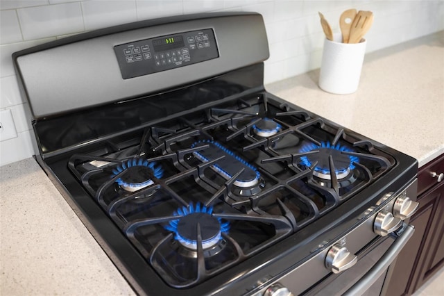 detailed view of stainless steel gas range oven, dark brown cabinets, and light stone countertops