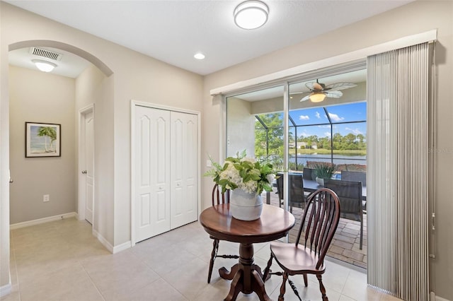dining space with ceiling fan, arched walkways, a sunroom, baseboards, and light tile patterned floors