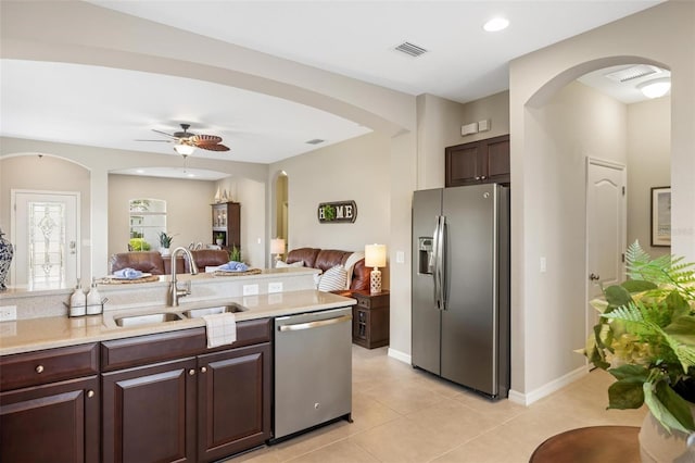 kitchen featuring stainless steel appliances, arched walkways, a sink, light countertops, and open floor plan