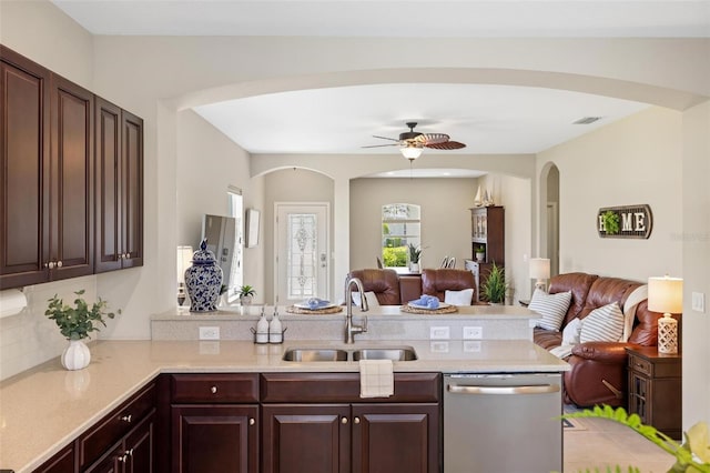 kitchen featuring stainless steel dishwasher, a sink, arched walkways, open floor plan, and a peninsula