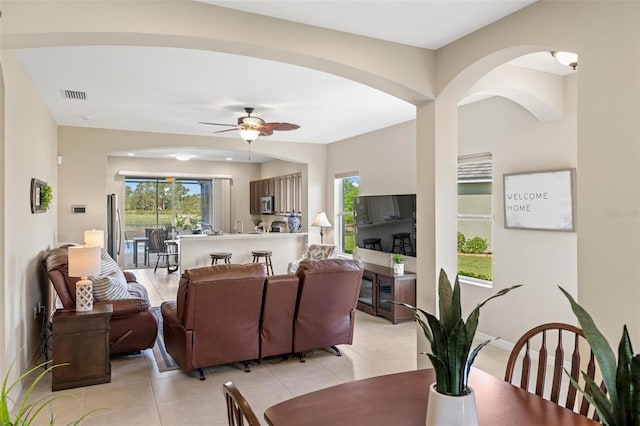 dining area with ceiling fan, arched walkways, and light tile patterned floors