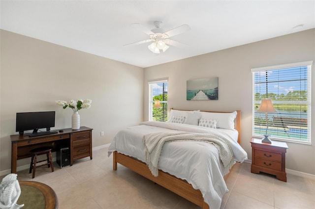 bedroom with baseboards, light tile patterned floors, ceiling fan, and an office area