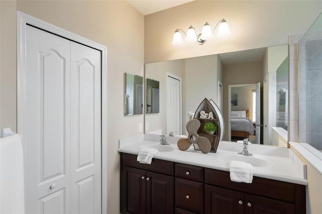 ensuite bathroom featuring double vanity, a closet, and a tile shower