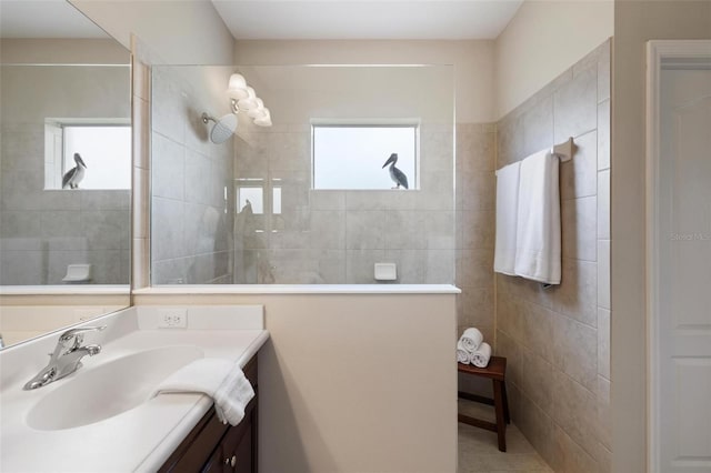 full bathroom featuring walk in shower, vanity, and tile walls
