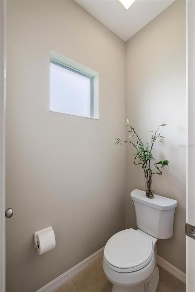 bathroom featuring toilet, baseboards, and tile patterned flooring