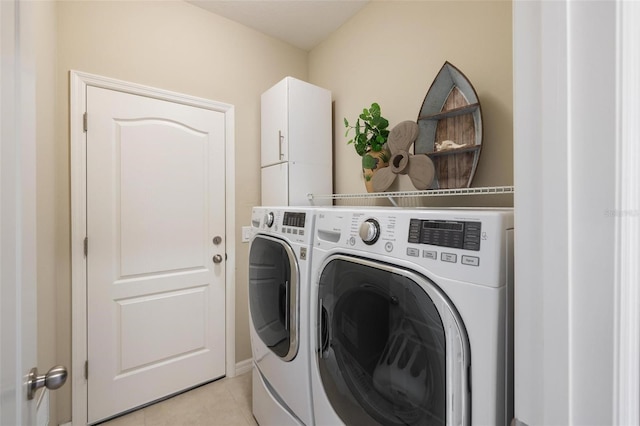 laundry area featuring separate washer and dryer, light tile patterned floors, and cabinet space