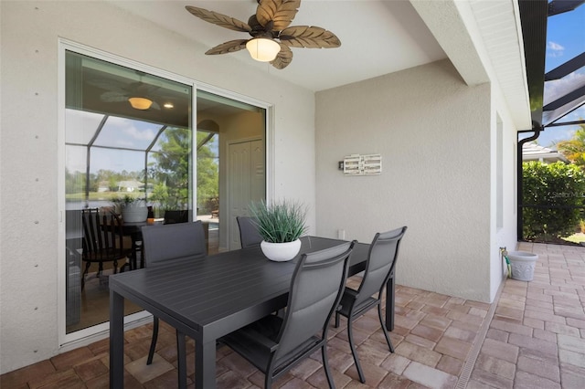 view of patio featuring ceiling fan and glass enclosure