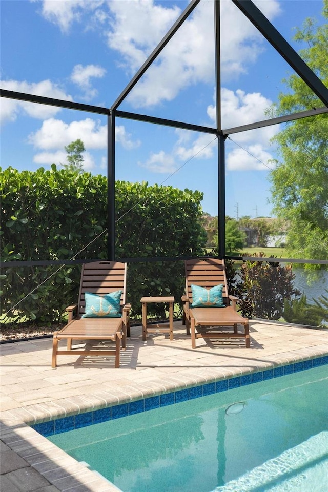 swimming pool with a patio area and glass enclosure