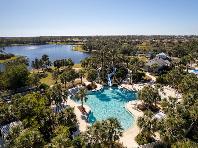 aerial view of a pool, a nearby body of water, and a tree filled landscape