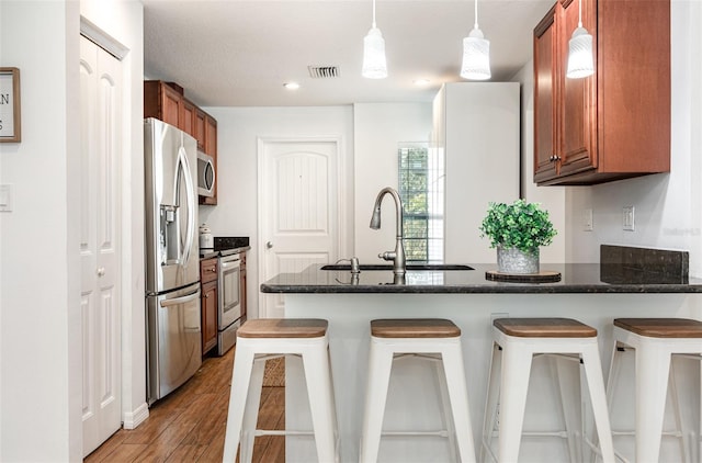 1345 24th St, Sarasota, FL 34234 - kitchen with appliances with stainless steel finishes, a sink, a peninsula, wood finished floors, and brown cabinets