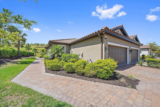 6250 Grandview Hill Ct, Bradenton, FL 34203 - view of side of property with a garage, stucco siding, decorative driveway, and a tiled roof