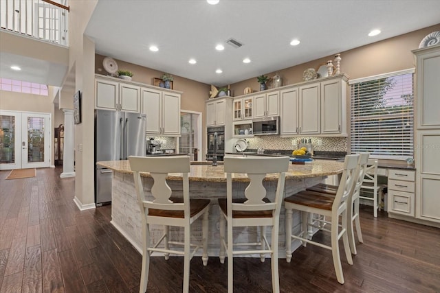 6907 47th Ct E, Ellenton, FL 34222 - kitchen featuring stainless steel appliances, tasteful backsplash, an island with sink, dark wood-style floors, and glass insert cabinets