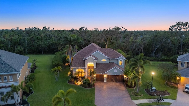 6907 47th Ct E, Ellenton, FL 34222 - view of front of home featuring driveway, a front lawn, a wooded view, and an attached garage