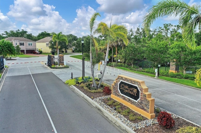 6907 47th Ct E, Ellenton, FL 34222 - view of asphalt road with street lights, curbs, a gated entry, and view of wooded area