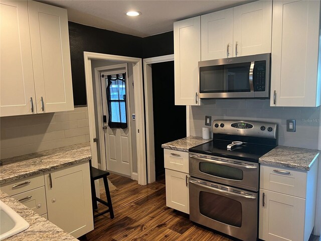 kitchen featuring stainless steel appliances, dark wood finished floors, decorative backsplash, white cabinets, and recessed lighting