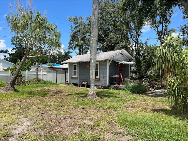 rear view of house featuring an outdoor structure and roof with shingles