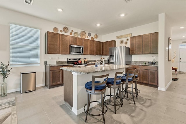 8628 Milestone Dr, Sarasota, FL 34238 - kitchen with appliances with stainless steel finishes, a sink, a kitchen bar, a kitchen island with sink, and light stone countertops
