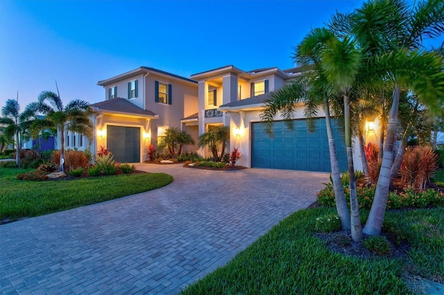 mediterranean / spanish home with decorative driveway, stucco siding, a tiled roof, and an attached garage