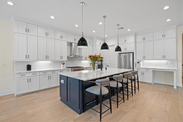 kitchen with wall chimney exhaust hood, tasteful backsplash, white cabinets, high end refrigerator, and light wood-type flooring