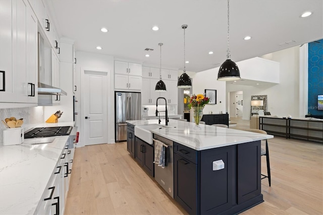kitchen with a sink, stainless steel appliances, white cabinetry, light wood-style flooring, and recessed lighting
