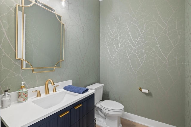 half bathroom featuring toilet, vanity, and wood finished floors