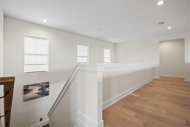 hall with an upstairs landing, wood finished floors, recessed lighting, and baseboards