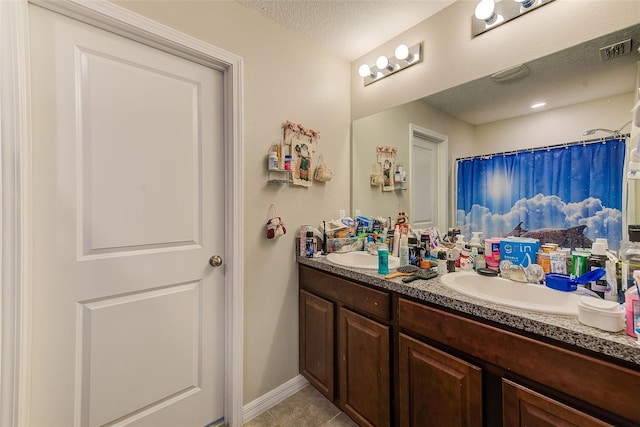 10944 Rainbow Pyrite Dr, Wimauma, FL 33598 - full bathroom featuring double vanity, tile patterned floors, a textured ceiling, baseboards, and a shower with shower curtain