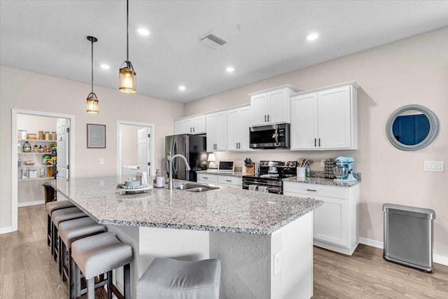 16411 62nd Gln E, Parrish, FL 34219 - kitchen with stainless steel appliances, an island with sink, a kitchen bar, light wood-type flooring, and recessed lighting