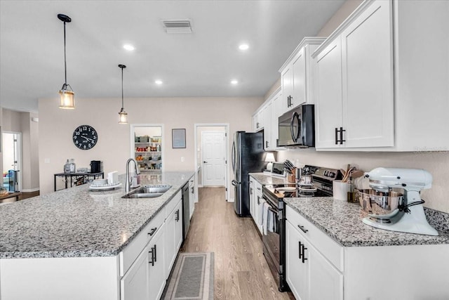 16411 62nd Gln E, Parrish, FL 34219 - kitchen featuring black appliances, a sink, a kitchen island with sink, light wood-style floors, and white cabinets