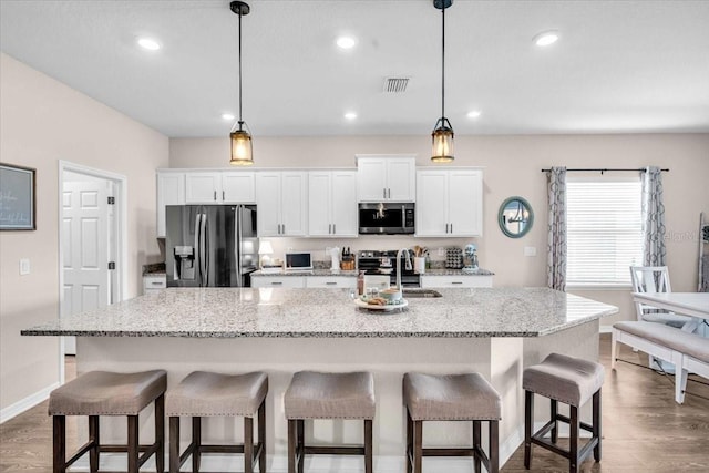16411 62nd Gln E, Parrish, FL 34219 - kitchen featuring stainless steel appliances, a sink, white cabinetry, an island with sink, and dark wood finished floors
