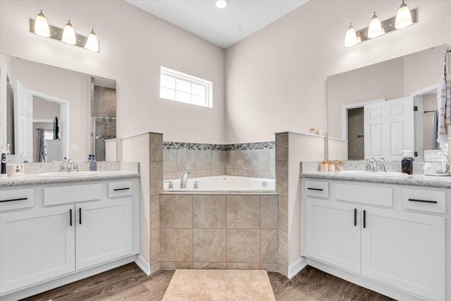 16411 62nd Gln E, Parrish, FL 34219 - full bathroom featuring two vanities, a garden tub, a tile shower, and wood finished floors