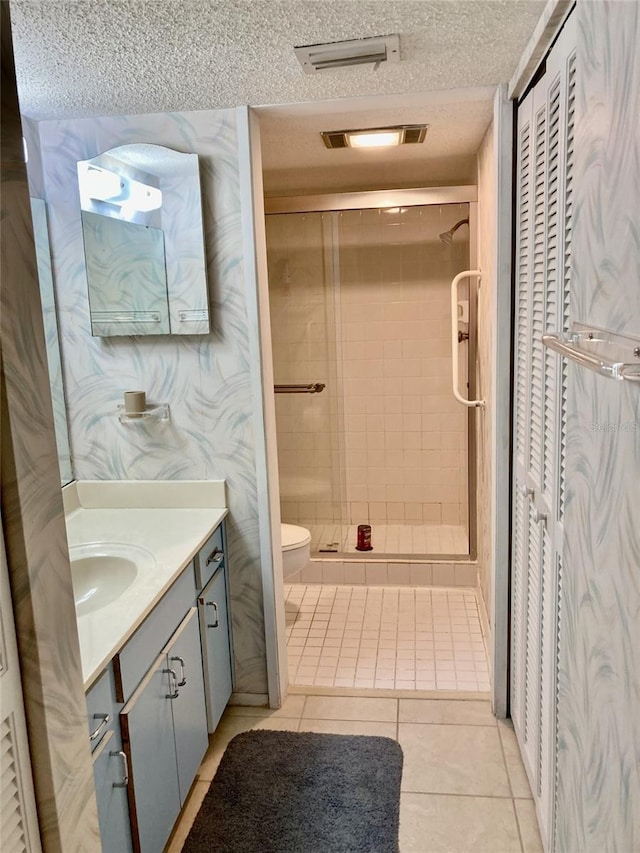 6124 43rd St W Unit 104A, Bradenton, FL 34210 - bathroom featuring a textured ceiling, a shower stall, vanity, tile patterned flooring, and toilet